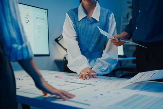 Start up Asia businesspeople meeting plan analysis statistics brainstorm and work with paperwork around table in office conference room at night. Business finance partners strategy investment success.