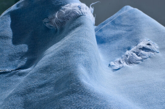 Close-up of striking ripped jeans, revealing a touch of rebelliousness and daring in fashion. Ideal for those who want to convey an audacious attitude.