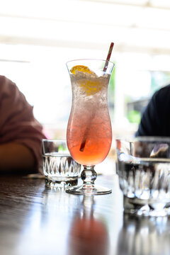Frosty pink cocktail with citrus garnish and striped straw.
