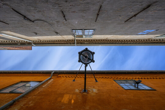 Dramatic upward view between old buildings and sky.
