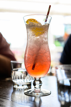 Close up pink iced cocktail with orange slice garnish.