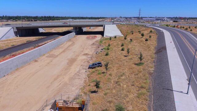Still Aerial Drone Shot Over Crashed Car Near California High Speed Rail Construction With Freeway Overpass Power Lines and Intrusion Barrier Wall in Fresno California