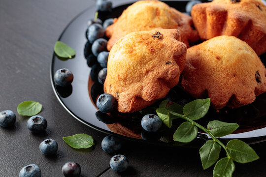 Freshly baked blueberry muffins on a black plate.