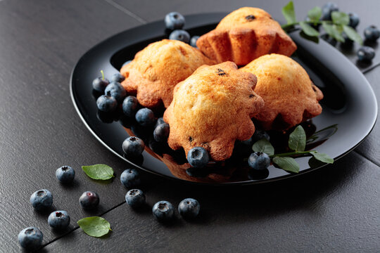 Freshly baked blueberry muffins on a black plate.