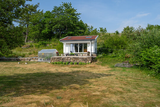 Small garden house with greenhouse in rural landscape.