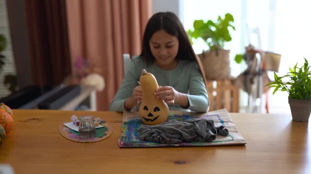 Female child painting pumpking during fall season for Halloween event - Holiday, childhood and autumn lifestyle concept	