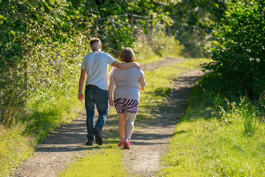 Companions embracing while walking together on quiet forest path.