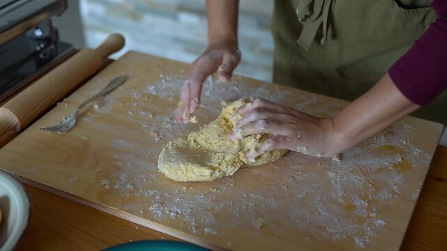 Woman doing homemade pasta indoor while kneading dough - Culture, italian food and lifestyle concept	