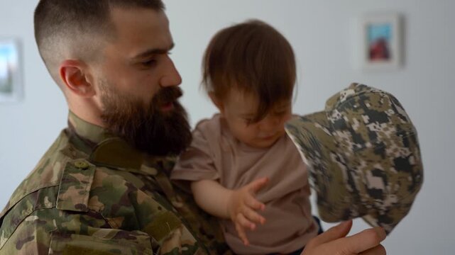 Male soldier in military uniform returning home to family - Father hugging baby son - Homecoming, happiness and love concept
