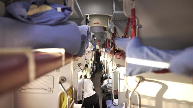 Long-distance train compartment with bunk beds and passengers traveling