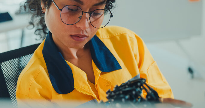 Close-up young Black female engineer coding AI robot arm in modern laboratory. Robotics, artificial intelligence, technology, stem, future, innovation, diversity, automation, machine learning concept.