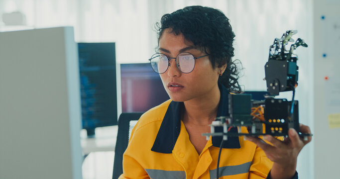 Young Black female engineer coding AI robot arm in modern laboratory. Robotics, artificial intelligence, technology, stem, future, innovation, diversity, automation, machine learning concept.