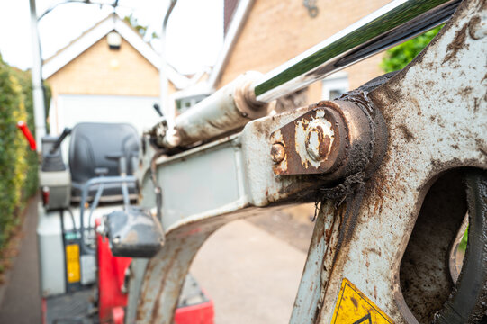 Shallow focus of the pivot of a mechanical digger and excavator showing the hydraulic piston and pipes. Seen on a private driveway before being excavated.