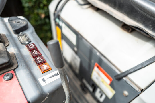 Shallow focus of the control panel and level of a small mechanical digger and excavator. Under the drivers seat is the small petrol engine.