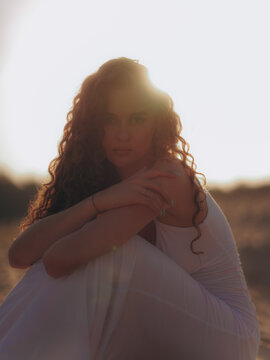 Amputee Woman Sitting on Sand Dune Backlit by Sunset