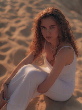 Amputee Woman Sitting on Sand Dunes Backlit by Sunset