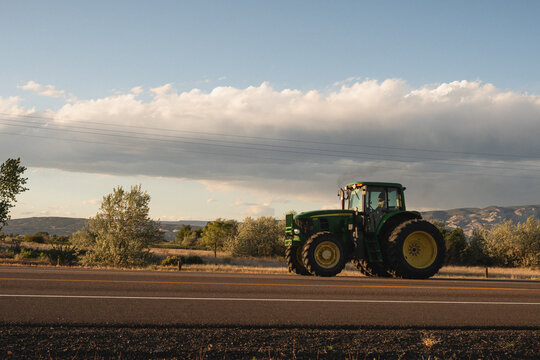 John Deere tractor driving down a rural road at sunset, Jensen, Utah, May 2025