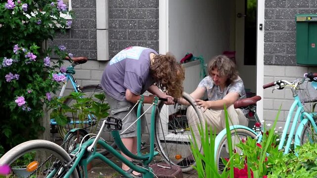 Father and son repairing turquoise bicycle in green courtyard