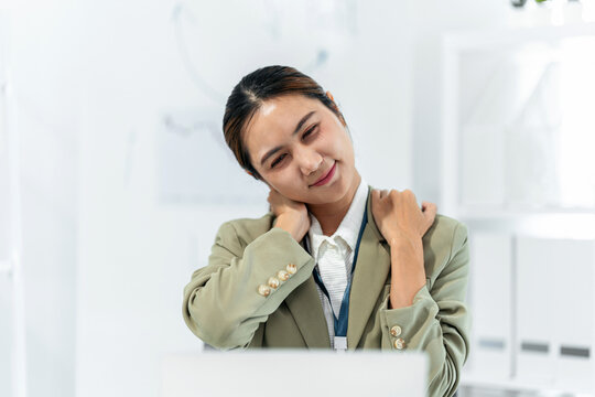 Professional woman stretches neck shoulders relieving pain fatigue stress at modern office workplace employee experiencing work discomfort