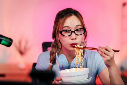 Professional gamer enjoying quick instant noodle meal at desk with headphones during streaming session