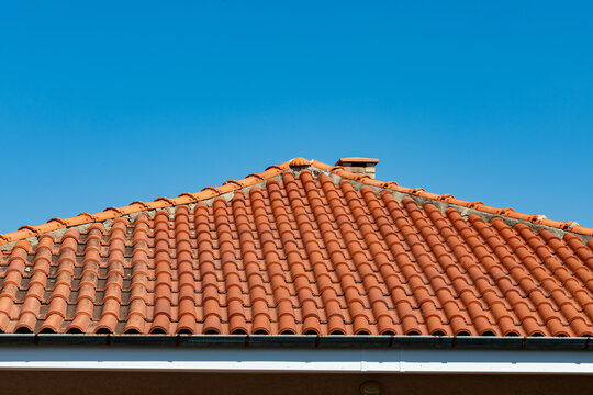 Close-up of a terracotta tiled roof under a clear blue sky, highlighting architecture, pattern, and vibrant color for construction or real estate concepts.