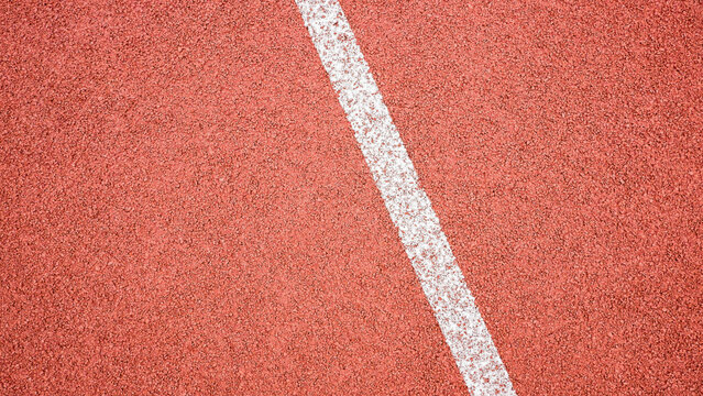 Red synthetic rubber running track surface with white lane line