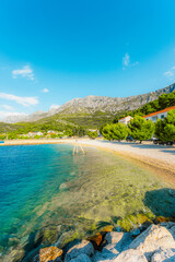 Stunning pebble beach in Drvenik with crystal clear turquoise water and the Biokovo mountain in the...