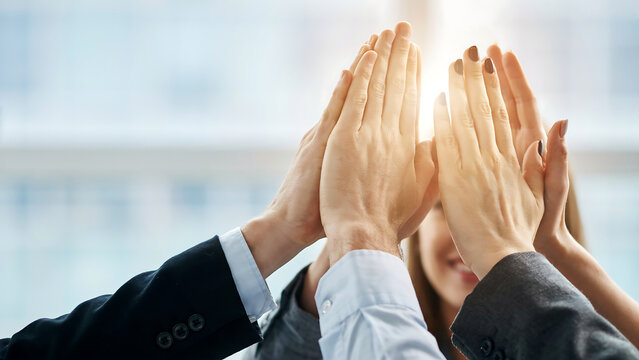 Business team members joining hands in a high five celebration gesture with teamwork collaboration business cooperation corporate partnership achievement agreement professional together
