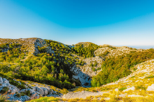 Rugged karst landscape of Biokovo Nature Park with white limestone rocks and sparse mediterranean vegetation, Dalmatia, Croatia.
