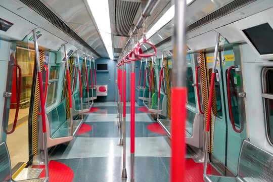 Modern subway train carriage with rows of vacant seats and bright overhead lights during a quiet transit journey through the city tunnels of Hong Kong