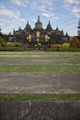 Obraz premium Magnificent mini replica of Borobudur temple surrounded by lush gardens, pathways, and golden Buddha statues under a blue sky at Brahma Vihara Arama monastery in Bali.