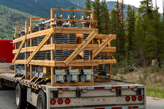 Heavy electrical equipment safely secured on a flatbed trailer with wooden supports and straps, illustrating industrial freight transportation, logistics, cargo delivery, and infrastructure in the USA