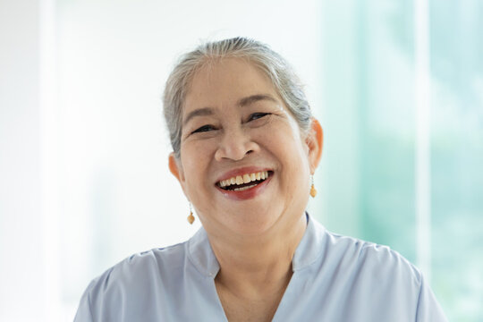 Happy joyful laughing old asian woman, female silver generation person with white hair showing positive friendly expressions, feeling good in home, indoors scene