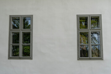 Fototapeta premium Two old, renewed grey wooden windows on white wall close up shot.