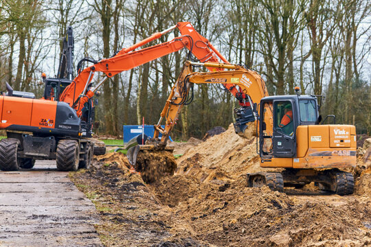 Heavy construction and civil engineering project two excavators filling a trench in Hoogeveen Netherlands