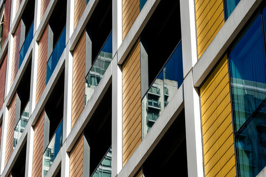 Yellow color accents the facade of residential apartments in London, Isle of Dogs, England, where windows and balconies create crisp geometry.