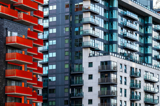 Red balconies bring color to residential apartments in London, Isle of Dogs, England, as the facade builds a dense and graphic urban pattern.