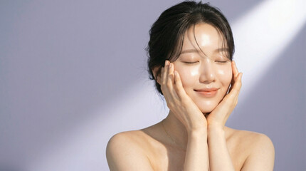 Fototapeta premium Young Asian Woman With Radiant Glowing Skin Touching Her Face In Soft Sunlight For Skincare Beauty Campaign