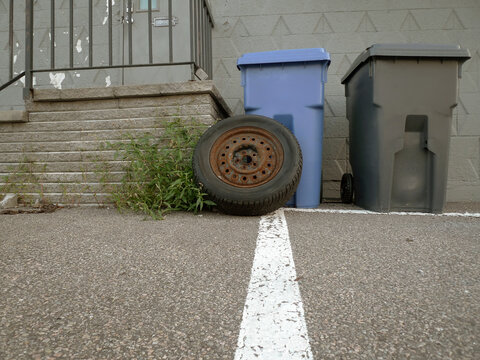 Des poubelles et un vieux pneu. Poubelles devant une maison au Qu&eacute;bec, Canada