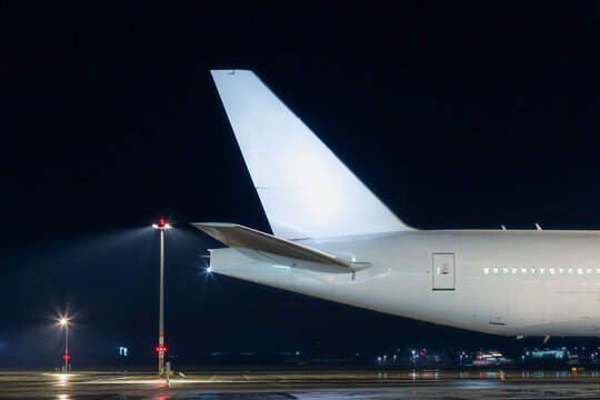 Illuminated commercial passenger airplane on airport tarmac at night. Air transportation industry, international flight infrastructure and aviation concept.
