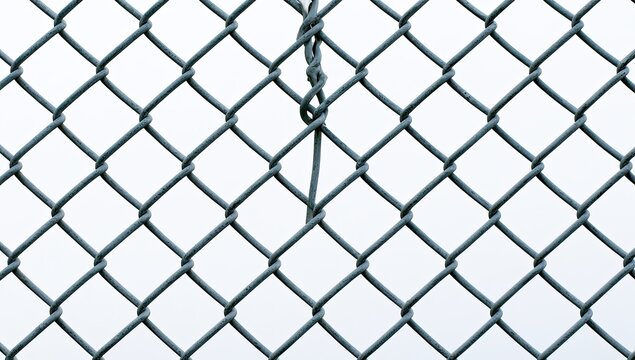 Close-up of a damaged chain-link fence with a broken wire.