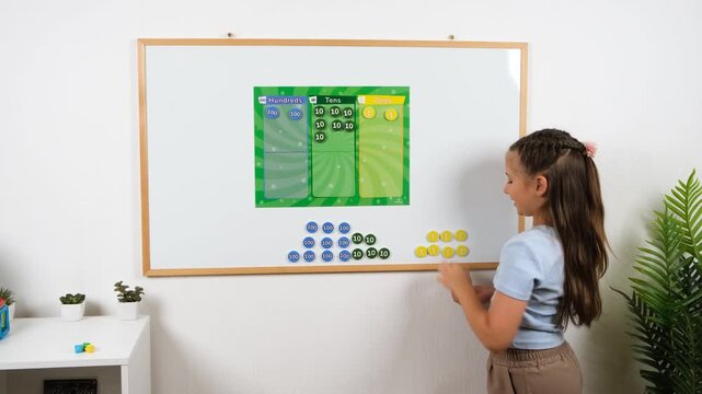 High-quality 4k video footage of a young schoolgirl practicing place value math exercise with hundreds tens and ones magnets on a whiteboard in bright room for education concept.
