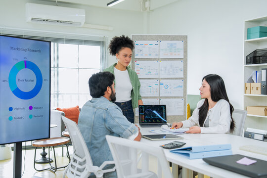 Three colleagues of different backgrounds gather closely around a tablet, engaged in a focused discussion of business data a genuine portrait of diverse teamwork and inclusive workplace collaboration
