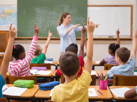 Diverse elementary students raising hands to answer teacher in a bright school classroom