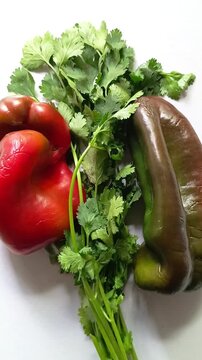 Fresh red and green sweet bell peppers with cilantro bunch on isolated white background in Guatemala