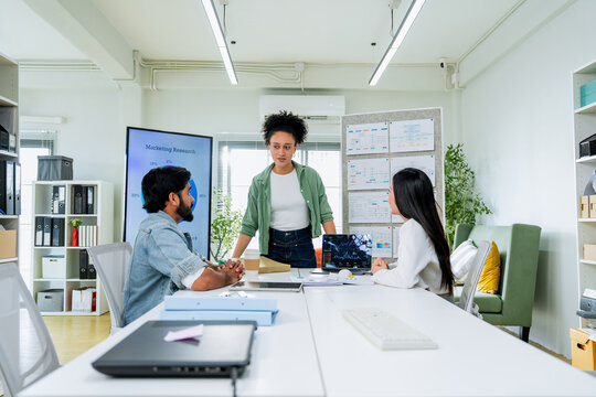 Three colleagues of different backgrounds gather closely around a tablet, engaged in a focused discussion of business data a genuine portrait of diverse teamwork and inclusive workplace collaboration