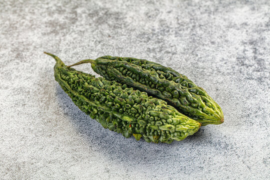 Two green bitter gourds on textured gray surface