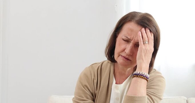 Mature woman has her hand on her forehead suffer from headache	
