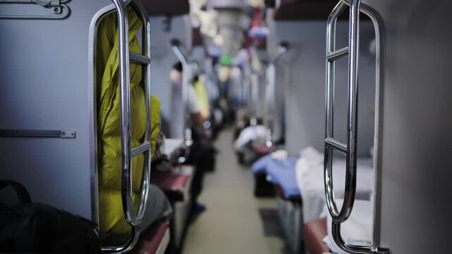 Train interior with aisle between berths, travelers on a long distance journey