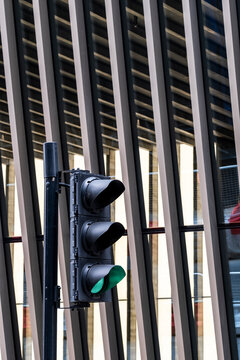 Vertical fins frame a green traffic signal against a close building view, while a street in London, England, reveals a rhythmic facade of urban architecture.